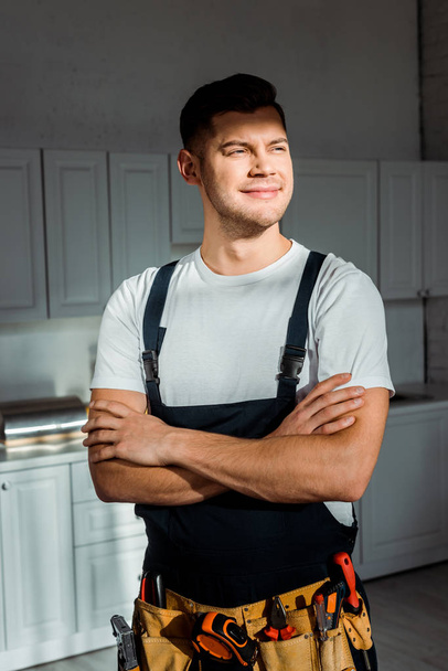sunshine on cheerful installer in overalls standing with crossed arms  - Photo, Image