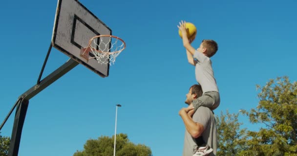 Padre e hijo jugando baloncesto en la calle y lanzando una pelota a la canasta
. - Metraje, vídeo