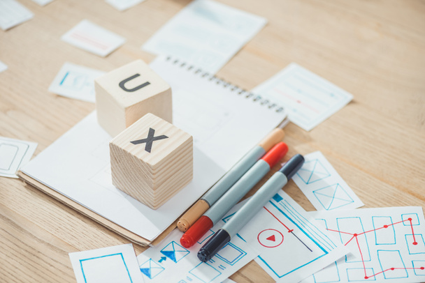 Selective focus of letters ux on cubes with website app development sketches on wooden table - Photo, Image