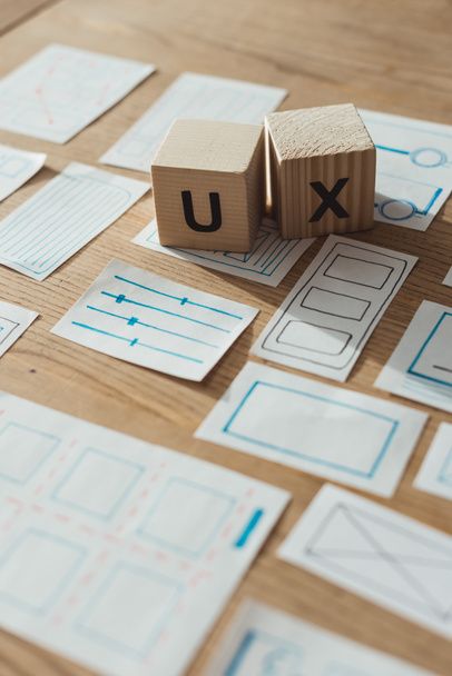 Selektivní zaměření dřevěných kostek s písmeny uxu podle náčrtků aplikace na stole  - Fotografie, Obrázek