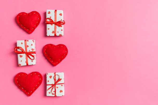 Holiday composition of gift boxes and red textile hearts on colorful background with empty space for your design. Top view of Valentine's Day concept - Photo, image