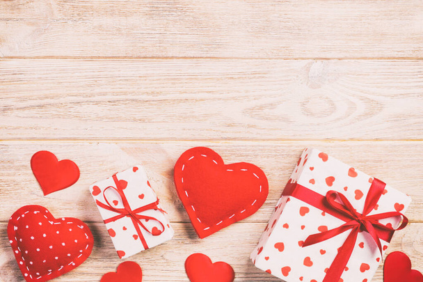 Sevgililer veya diğer tatil el yapımı mevcut kağıt ile tatil sarmalayıcı kırmızı kalpler ve hediye kutusunda. Tasarım için turuncu ahşap masa üstten görünüm kopya alanı ile boş alanı hediye kutusu - Fotoğraf, Görsel