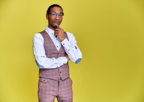 Portrait of a young African American man with short haircuts and a white-toothed smile in a business suit on a yellow background. Standing and talking right in front of the camera. - Photo, Image