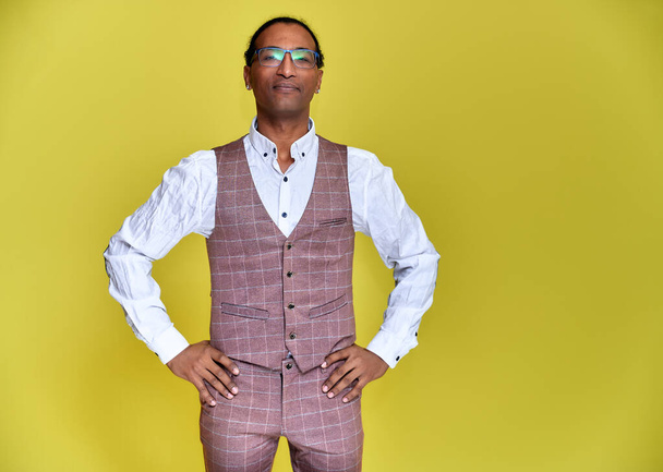 Portrait of a young African American man with short haircuts and a white-toothed smile in a business suit on a yellow background. Standing and talking right in front of the camera. - Foto, afbeelding