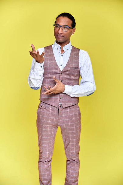 Vertical Portrait Young man with short-haired African American in a business suit on a yellow background. Standing and talking right in front of the camera. - Fotoğraf, Görsel