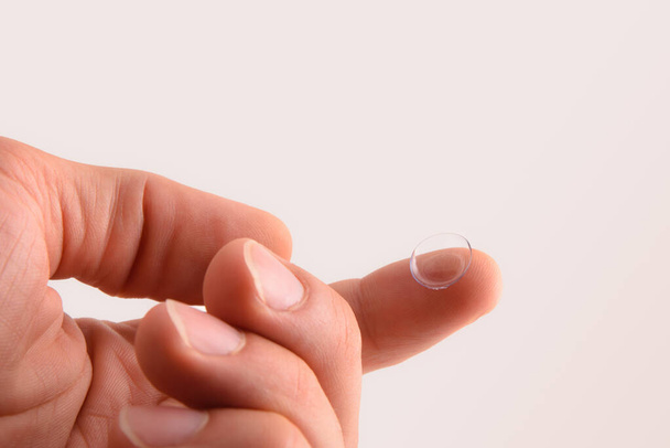 Ręka z soczewką kontaktową na palcu z izolowanym tłem - Zdjęcie, obraz