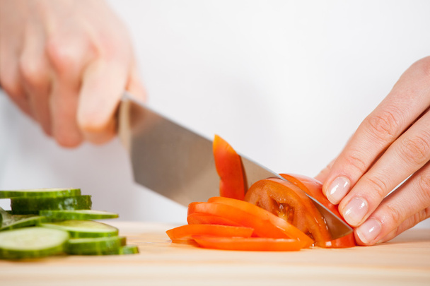 Female hands cutting fresh cucumber and tomato - Фото, изображение