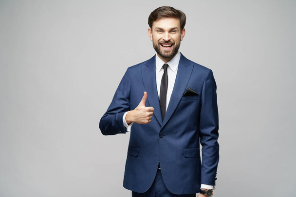 young business man going thumb up on grey background - Foto, afbeelding