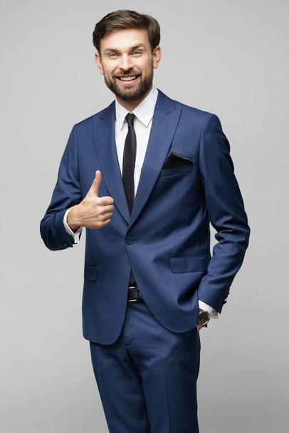 young business man going thumb up on grey background - Photo, Image