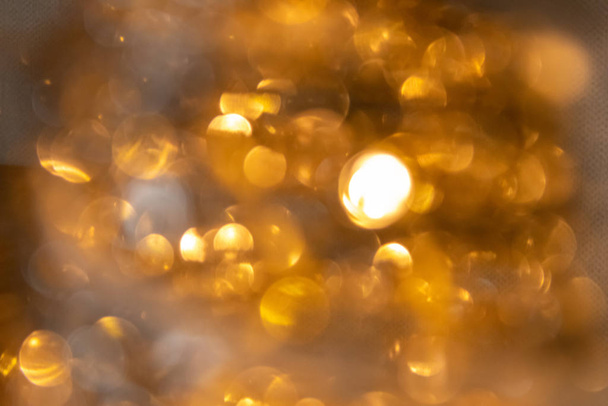 Όμορφη χρυσή bokeh φόντο υφή ενός στεφανιού Χριστουγέννων με χρυσά κλαδιά ως ανάλαφρη και εορταστική διακόσμηση κατά την έλευση του χρόνου και την παραμονή των Χριστουγέννων - Φωτογραφία, εικόνα