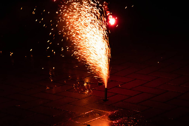Πολύχρωμα πυροτεχνήματα φωτίζουν τη νύχτα του Σιλβέστερ με πυροτεχνήματα, κροτίδες, κροτίδες και εκρηκτικά πυροτεχνήματα και συντριβάνια φωτός για να γιορτάσουν σε μια ευτυχισμένη νέα χρονιά σε ένα σιλβέστερ πάρτι με φίλους - Φωτογραφία, εικόνα