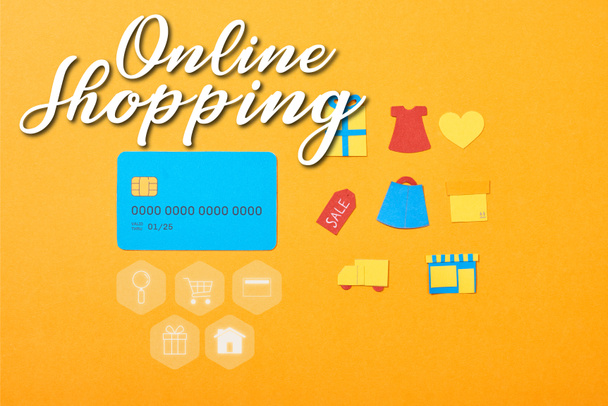 オンラインショッピングイラストでオレンジに隔離されたショッピングアイコンの近くに青いクレジットカードテンプレートとフラットレイ - 写真・画像