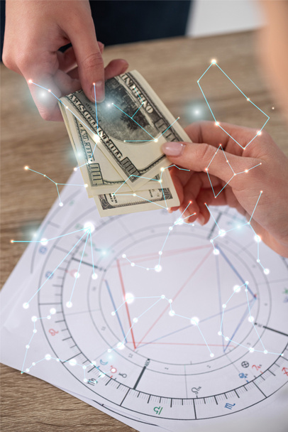 Gewassen beeld van de mens die geld geeft aan astroloog naast geboortehoroscopen en sterrenbeelden - Foto, afbeelding