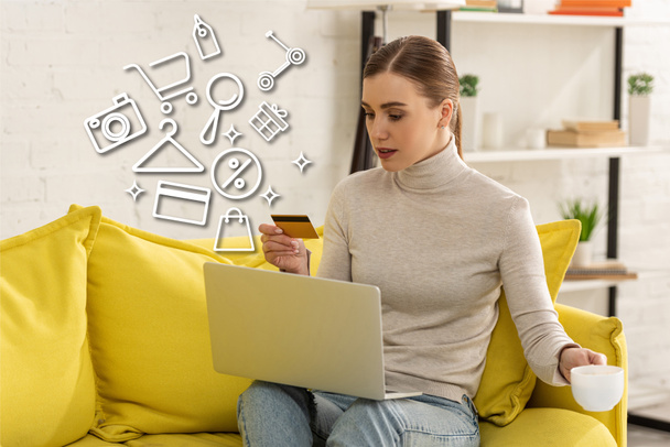 Attractive girl with credit card and coffee using laptop near illustration - Fotó, kép