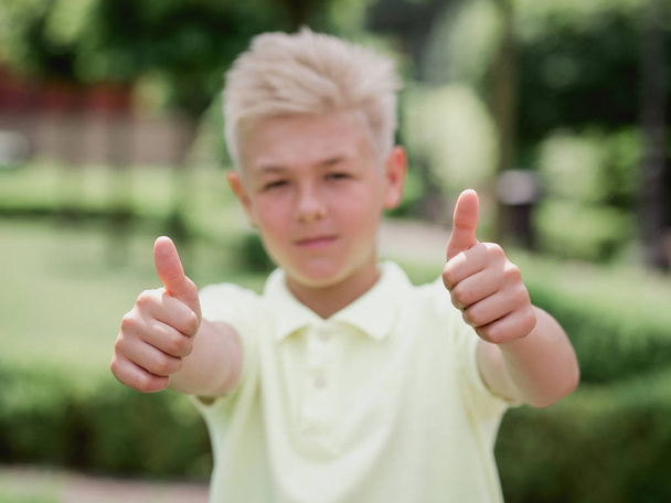 Portret przystojnej blondynki jedenaście stary chłopiec (nastolatek) z kciukiem (palce) w górę (ok) na zewnątrz. Dobry znak i ok pojęcie - Zdjęcie, obraz
