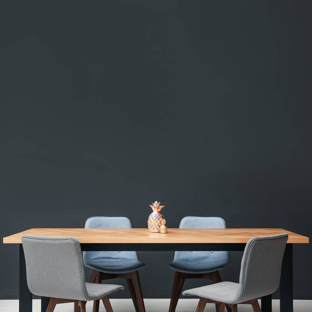 Moderne tafel met decoratieve ananas bij zwarte muur - Foto, afbeelding