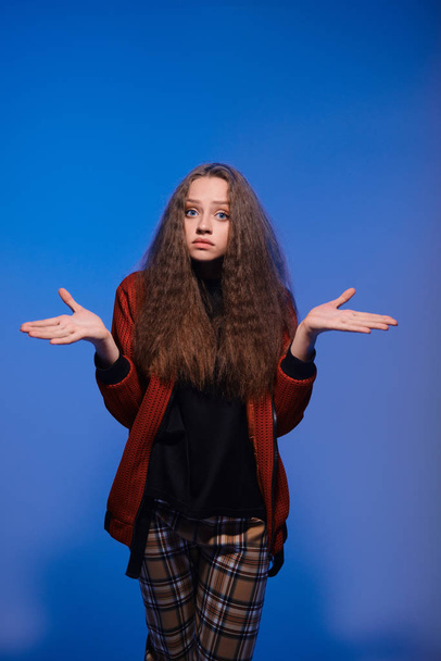 Cute teenager girl posing on blue background with divorced hands - Фото, зображення