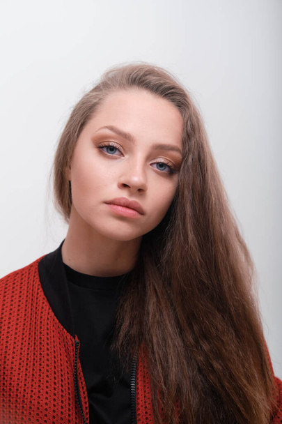 Teenager girl with fluffy hair wearing red jacket posing in studio - Φωτογραφία, εικόνα