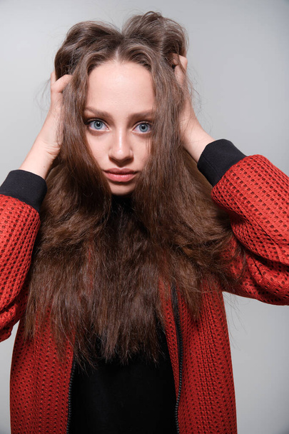 Teenager girl with fluffy hair wearing red jacket posing in studio - Zdjęcie, obraz