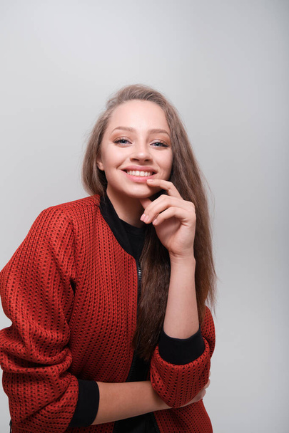 Teenager girl with fluffy hair wearing red jacket posing in studio - Photo, Image