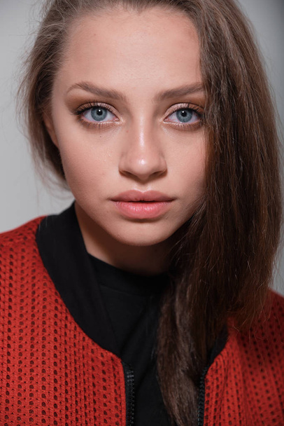 Teenager girl with fluffy hair wearing red jacket posing in studio - Foto, afbeelding