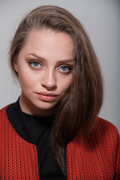 Teenager girl with fluffy hair wearing red jacket posing in studio - Fotó, kép