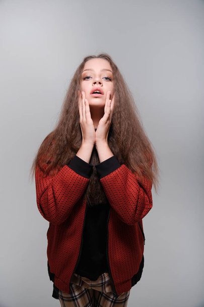 Teenager girl with fluffy hair wearing red jacket posing in studio - Foto, Bild