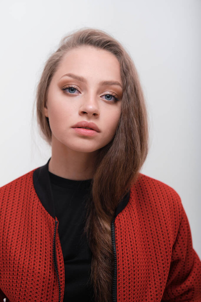 Teenager girl with fluffy hair wearing red jacket posing in studio - Фото, зображення