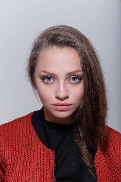 Teenager girl with fluffy hair wearing red jacket posing in studio - Foto, afbeelding