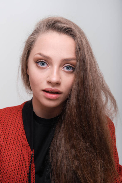 Teenager girl with fluffy hair wearing red jacket posing in studio - Fotoğraf, Görsel