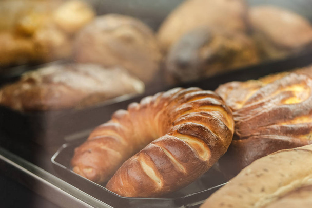 Za skleněným oknem pekárny leží mnoho různých druhů pečiva. - Fotografie, Obrázek