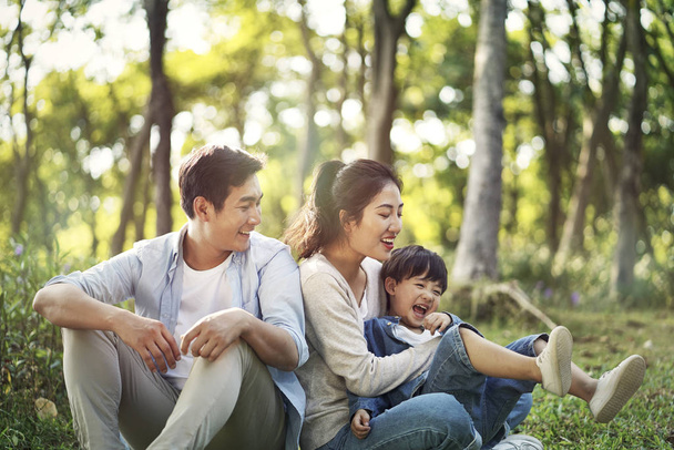familia asiática con un niño relajándose al aire libre
 - Foto, imagen