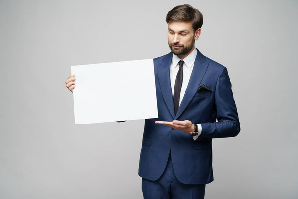Young businessman holding blank signs over grey background - 写真・画像