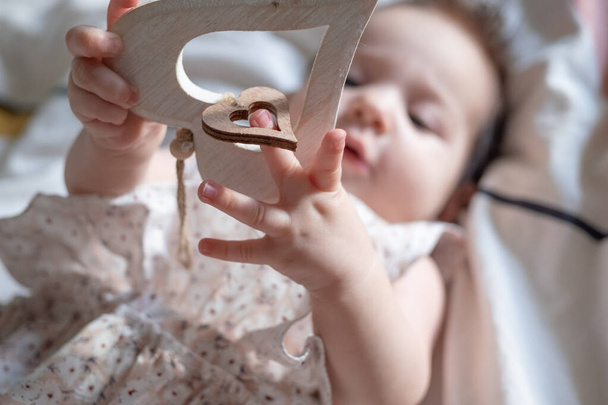 Little baby infant hands holding wooden rustic heart. selected focus. St. Valentines day concept - Photo, Image