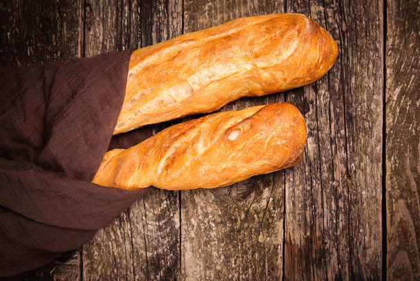 Κάτοψη του γαλλικού ψωμιού μπαγκέτας. Φρέσκες μπαγκέτες σε ξύλινο τραπέζι. Ψωμί. - Φωτογραφία, εικόνα