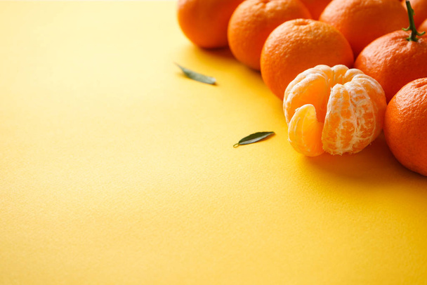 Oranžové mandarinky celé a oloupané na žlutém pozadí s místem pro text. - Fotografie, Obrázek