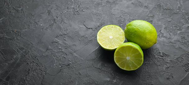 Green sliced lime on black stone background. Top view. free space for your text. Rustic style. - Zdjęcie, obraz