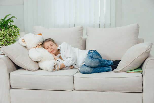 Sweet charming kid is lovely sleeping on her big white teddy-bear. Full-length. - Фото, зображення