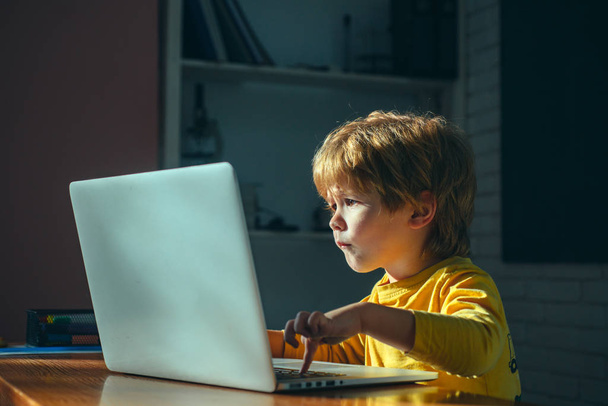 小さな男の子はダウンロードを待っているラップトップ画面を見ています。インターネットを検索します。新しい情報だ高速インターネット接続、遅い接続. - 写真・画像