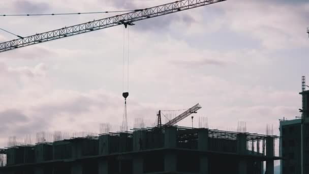 La grúa torre en un sitio de construcción eleva una carga en un edificio de gran altura
. - Metraje, vídeo