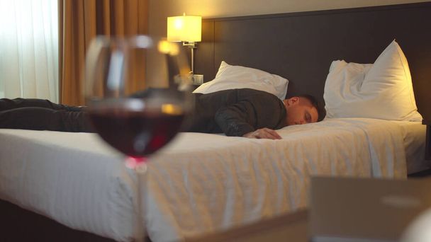 Man in suit sleep in hotel room on the background of glass of wine - Foto, imagen