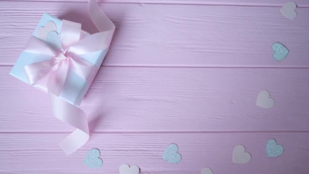 Подарочная коробка с лентой и конфетти в виде сердца на розовом деревянном фоне с местом для вашего текста. Видео в День Святого Валентина, День матери или День рождения. Top view HD
 - Кадры, видео