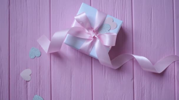 Подарочная коробка с лентой и конфетти в виде сердца на розовом деревянном фоне с местом для вашего текста. Видео в День Святого Валентина, День матери или День рождения. Top view HD
 - Кадры, видео