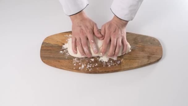 Male hands kneading dough in flour on a table and wooden board. Close up. - Video
