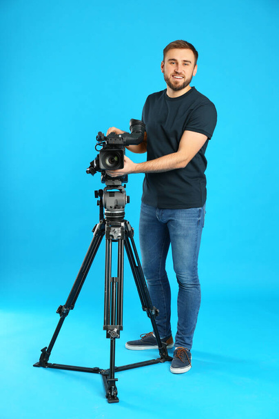 Operator with professional video camera on blue background - Photo, Image