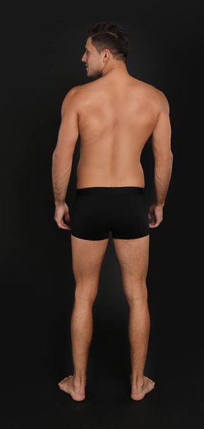 Man in underwear on black background, back view - Foto, afbeelding