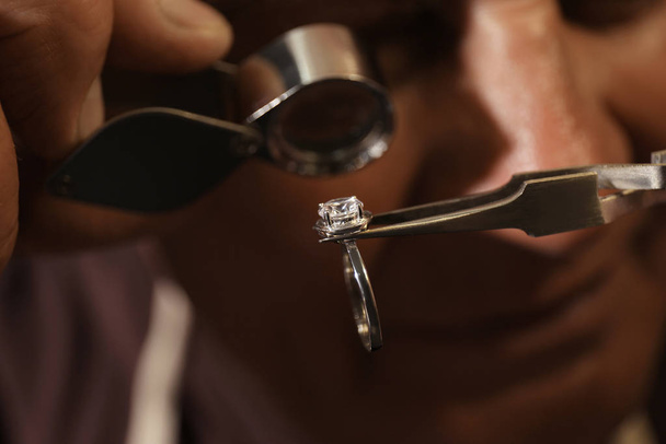Professional jeweler evaluating beautiful ring, closeup view - Valokuva, kuva