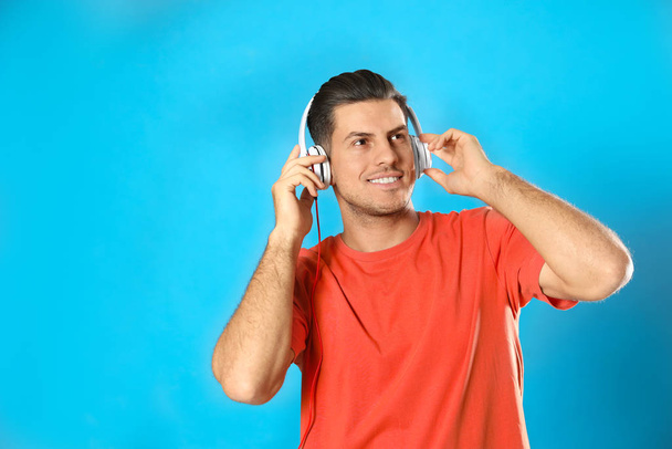 Man listening to audiobook on light blue background - Фото, зображення