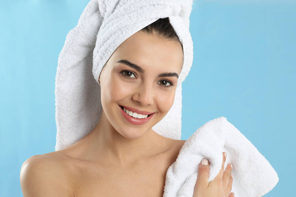 Young woman wiping body with towel on light blue background - Foto, imagen