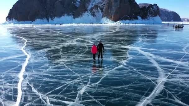 Frozen Lake Baikal. Beautiful winter landscape with clear smooth ice near rocky shore. The famous natural landmark Russia. Blue transparent ice with deep cracks. - Πλάνα, βίντεο